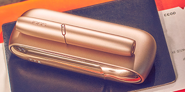 A gold IQOS 3 DUO holder and charger on a tablet