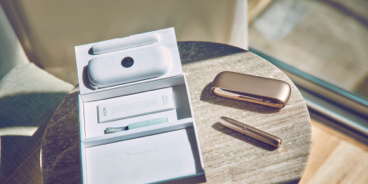 Gold IQOS DUO and its packaging on a round table