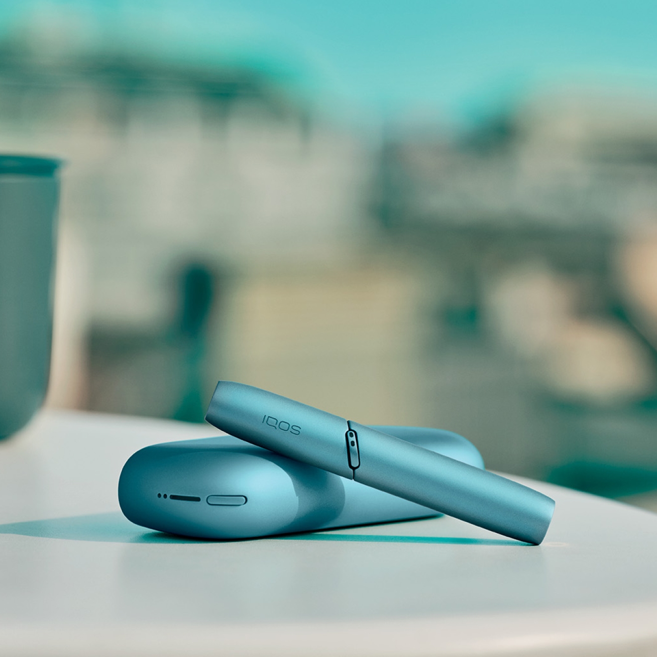 Turquoise IQOS Originals Duo  holder and pocket charger on table.