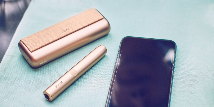 IQOS ILUMA ONE držač i džepni punjač pokraj mobitela.