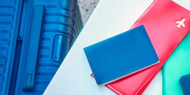 A passport, plane ticket, and IQOS device on a desk.