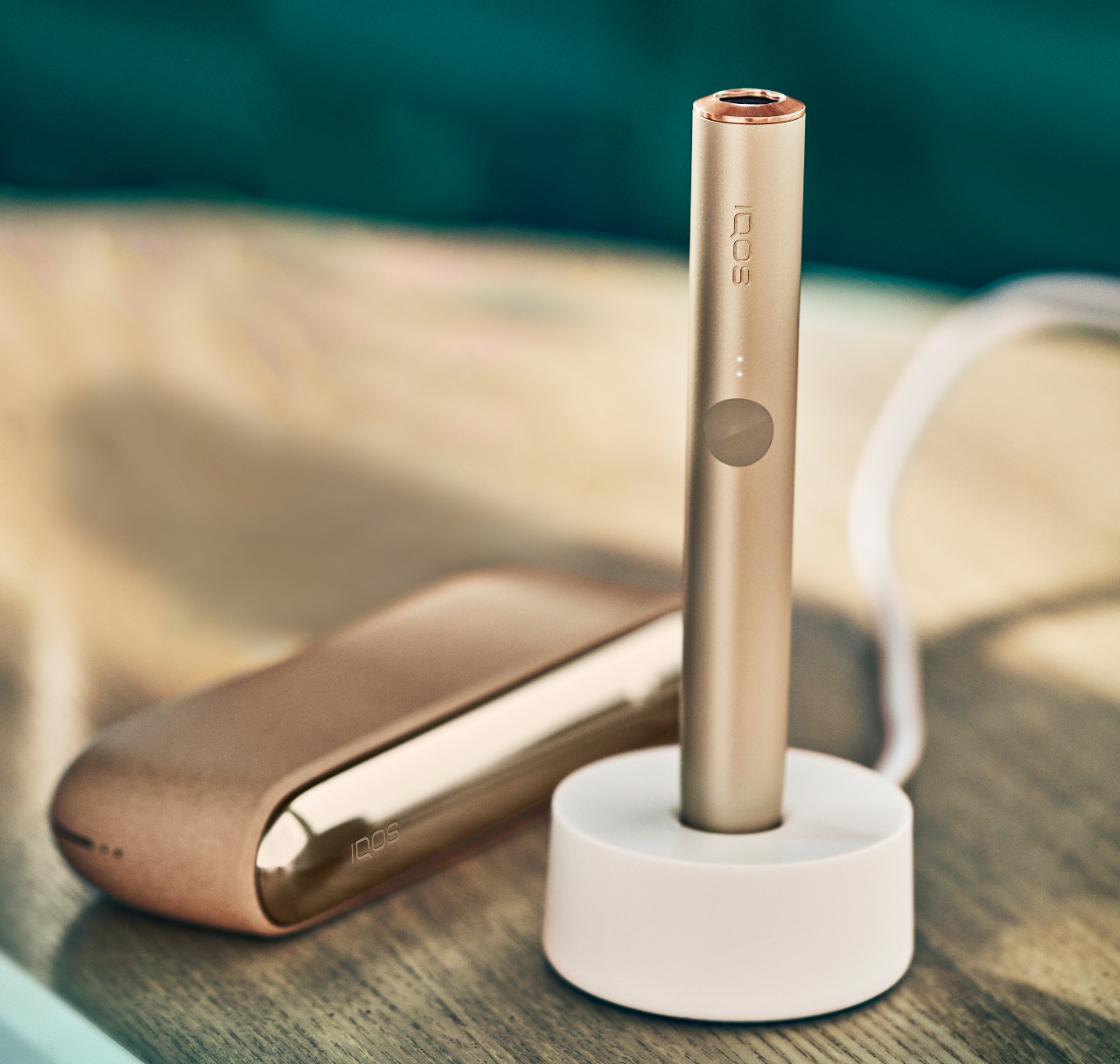 Krupni kadar Gold Khaki zlatnog IQOS ILUMA uređaja na punjenju.