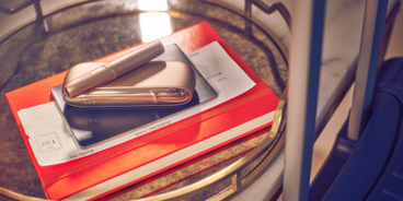 A gold IQOS DUO device on an orange copybook