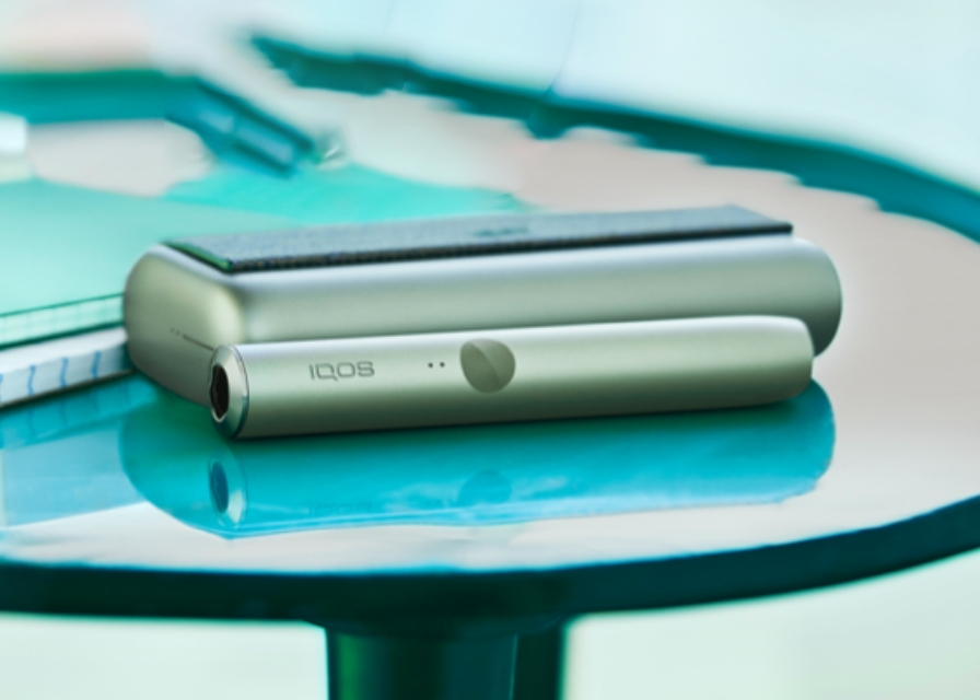 Jade Green zeleni IQOS ILUMA PRIME držač i džepni punjač na stolu.