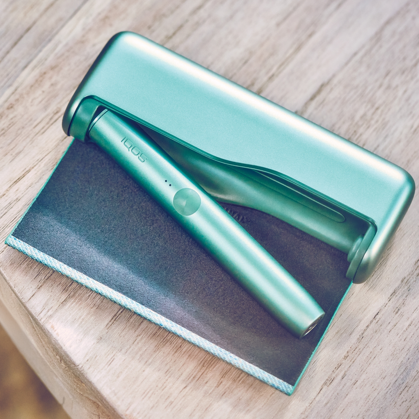 A jade green IQOS ILUMA PRIME pocket charger and holder.