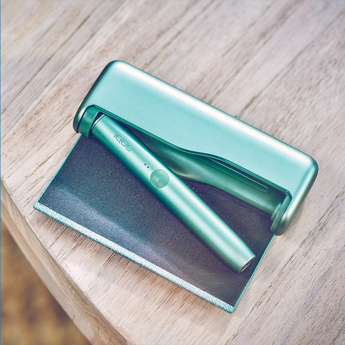 Jade Green IQOS ILUMA PRIME držač i džepni punjač na stolu.