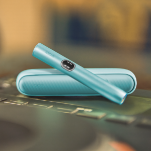 Blue IQOS ILUMA i device above its charger