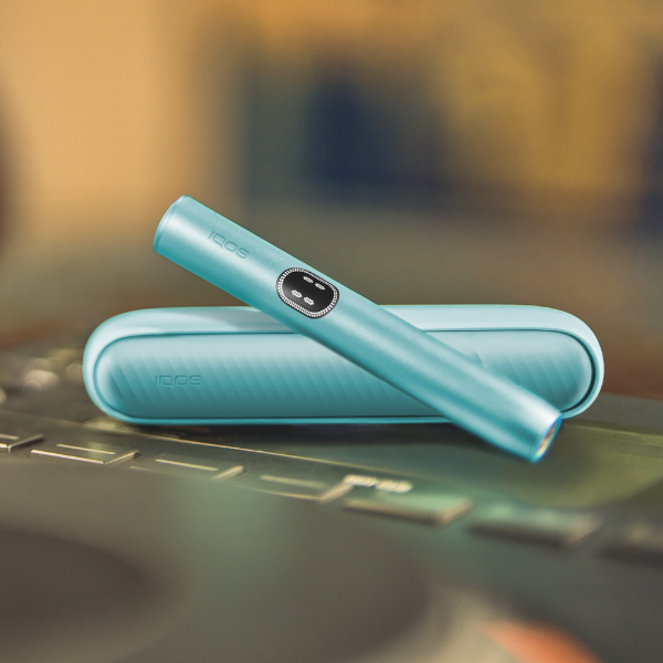 Blue IQOS ILUMA i device above its charger