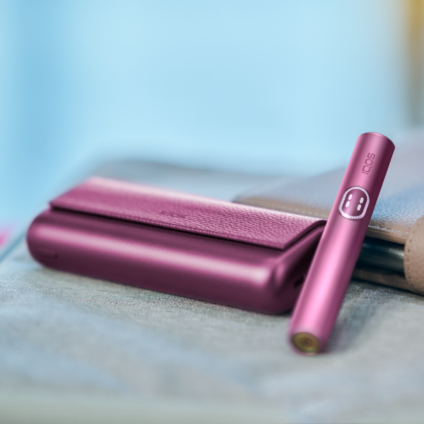 Držač IQOS ILUMA i PRIME uređaja u bordo Garnet Red boji pokraj džepnog punjača