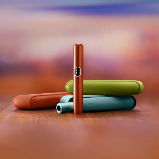 Red IQOS ILUMA i device standing in front of three different coulours chargers