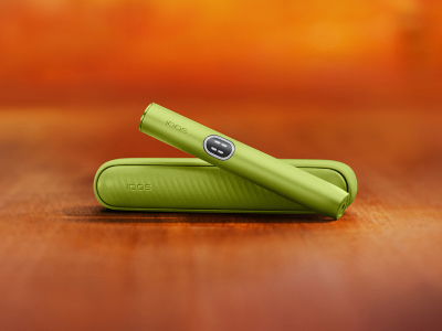 Green  IQOS ILUMA i device above its charger