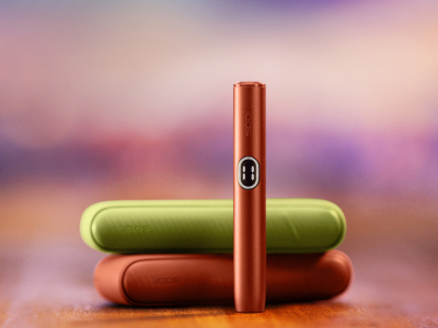 IQOS ILUMA i device standing in front of two chargers of different colours