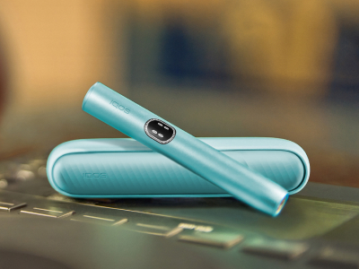 Blue IQOS ILUMA i device above its charger