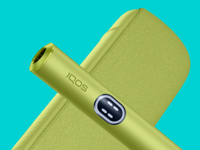 Green IQOS ILUMA i device above its charger