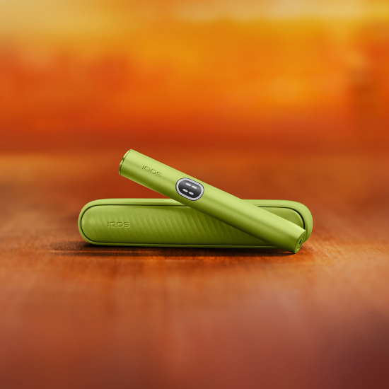 Green  IQOS ILUMA i device above its charger