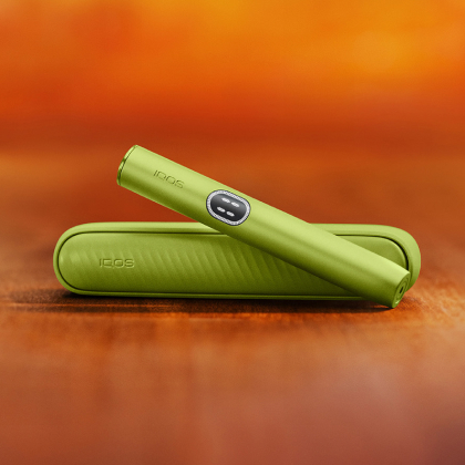 Green  IQOS ILUMA i device above its charger