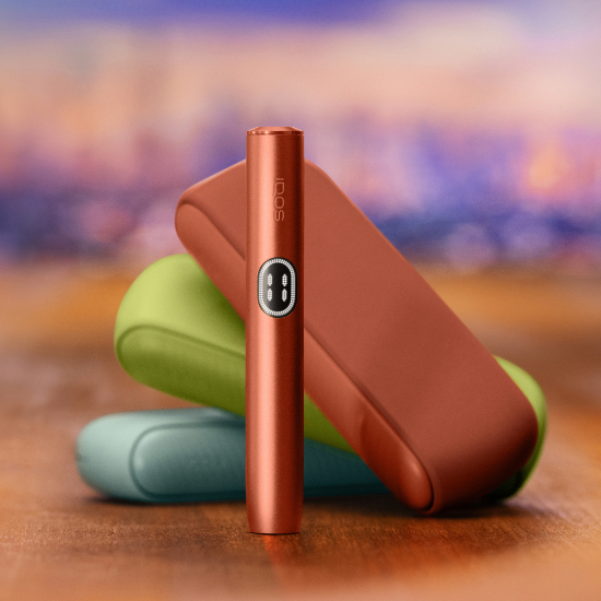 Red IQOS ILUMA i device standing in front of three different coulours chargers