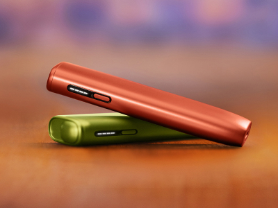 Crveni IQOS ILUMA i ONE uređaj na zelenom IQOS ILUMA i ONE uređaju