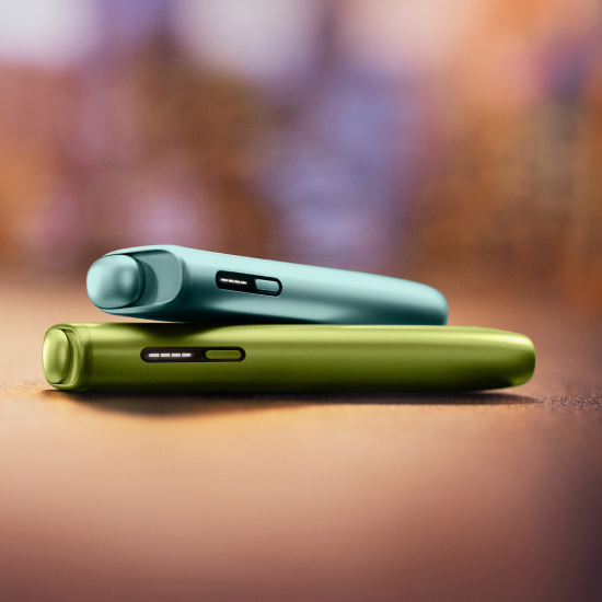 Plavi IQOS ILUMA i ONE uređaj na zelenom IQOS ILUMA i ONE uređaju