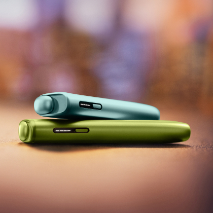 Plavi IQOS ILUMA i ONE uređaj na zelenom IQOS ILUMA i ONE uređaju