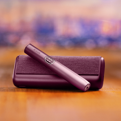Garnet Red IQOS ILUMA i PRIME device above its charger