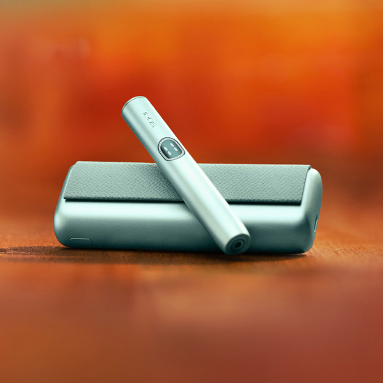 Breeze Blue IQOS ILUMA i device above its charger, with red background