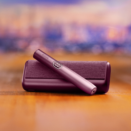 Garnet Red IQOS ILUMA i PRIME device above its charger