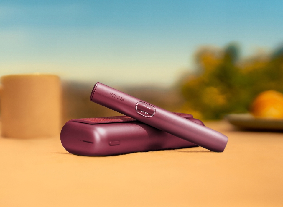 Garnet Red IQOS ILUMA i PRIME device above its charger