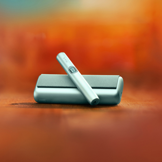 Breeze Blue IQOS ILUMA i PRIME device above its charger, with red background