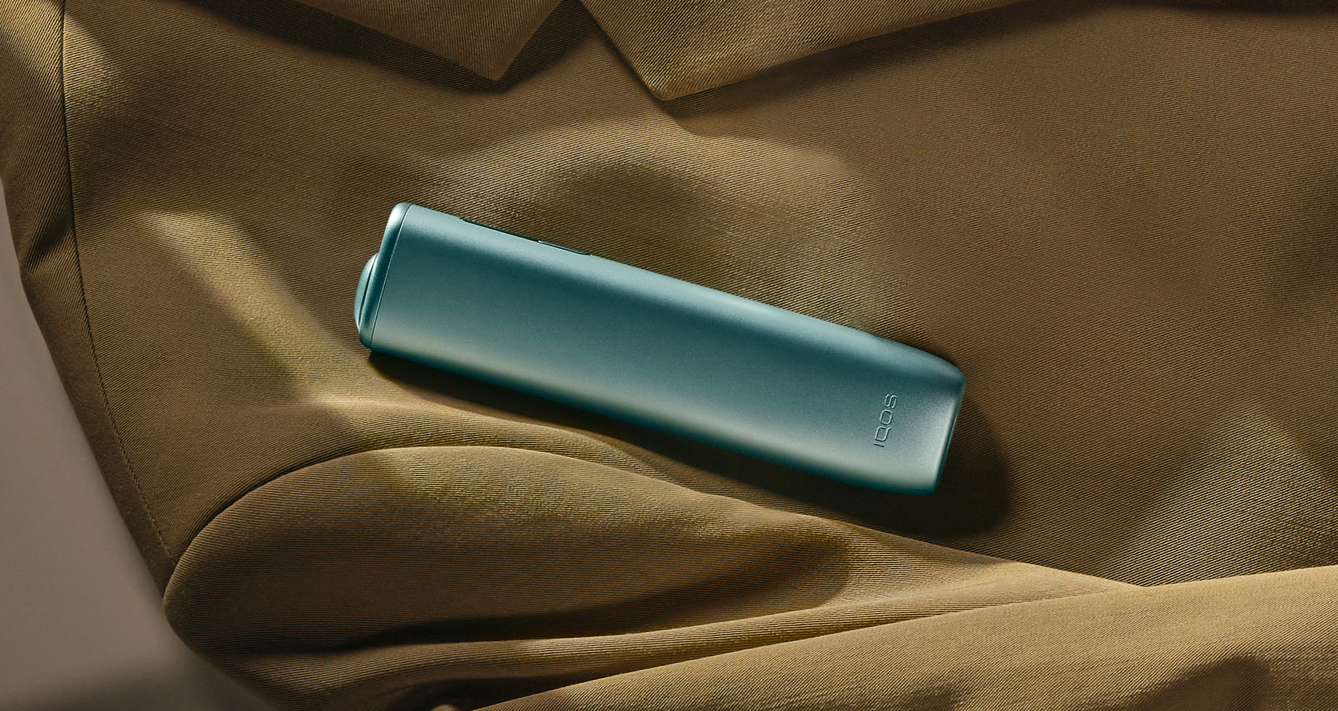 IQOS ILUMA i ONE uređaj u plavoj Breeze Blue boji položen na žuti sako