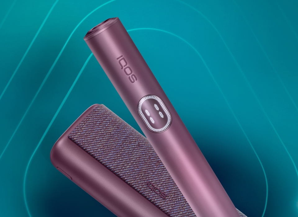 IQOS ILUMA i PRIME držač i džepni punjač u bordo Garnet Red boji na tamnotirkiznoj pozadini.