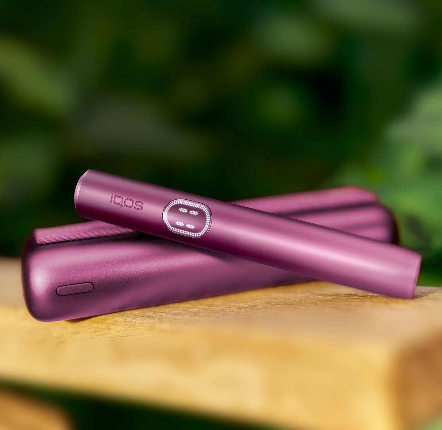 Garnet Red IQOS ILUMA i PRIME device above its charger