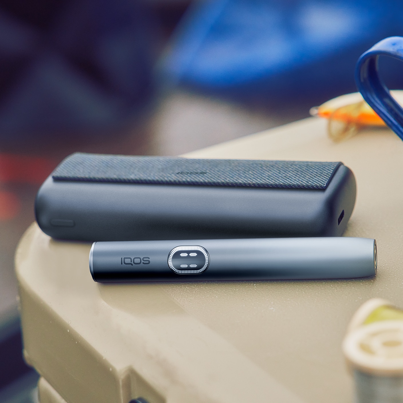 Midnight Black IQOS ILUMA i PRIME device next to its charger, on a table