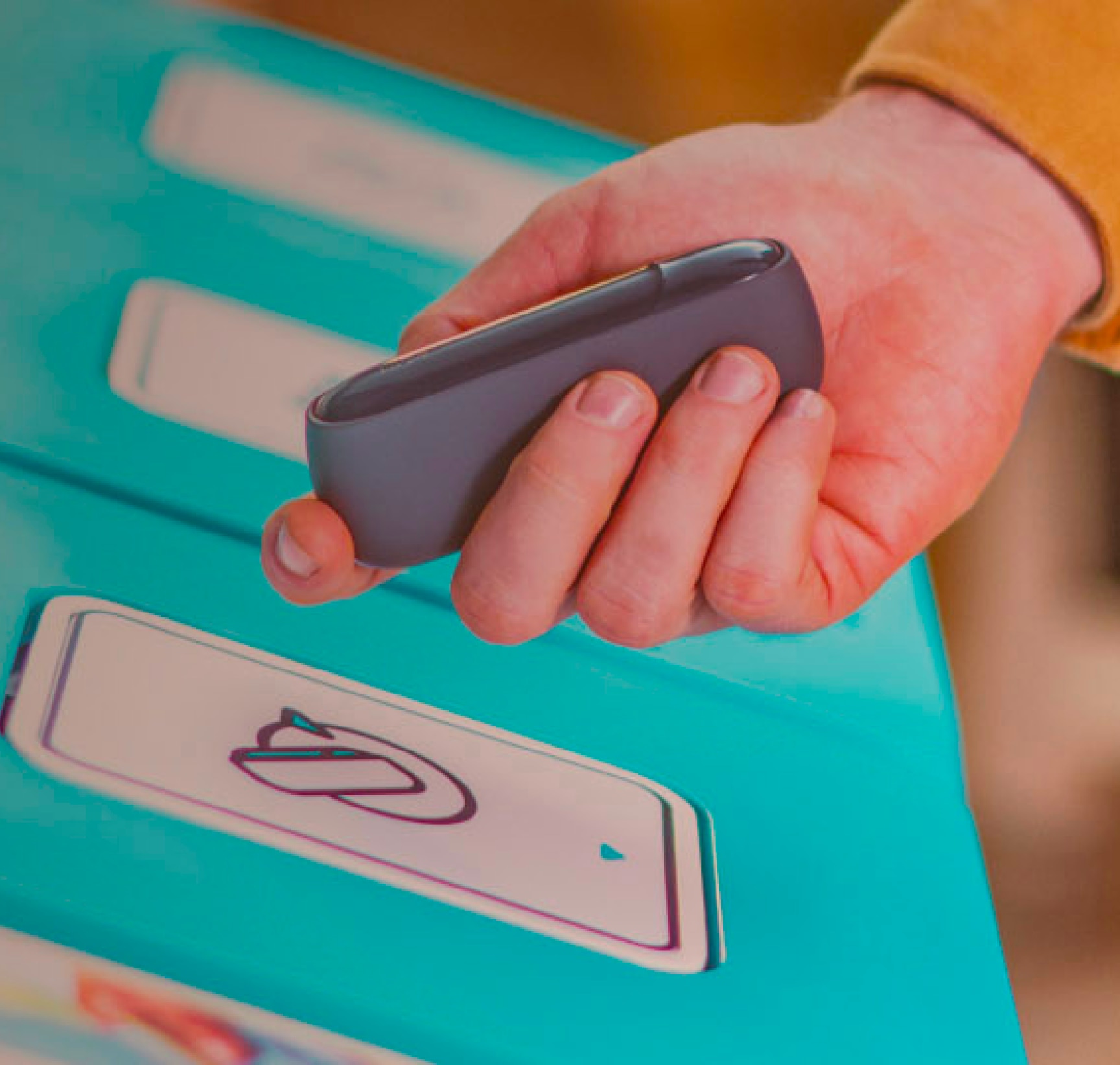 IQOS uređaj u ruci ispred koša za reciklažu