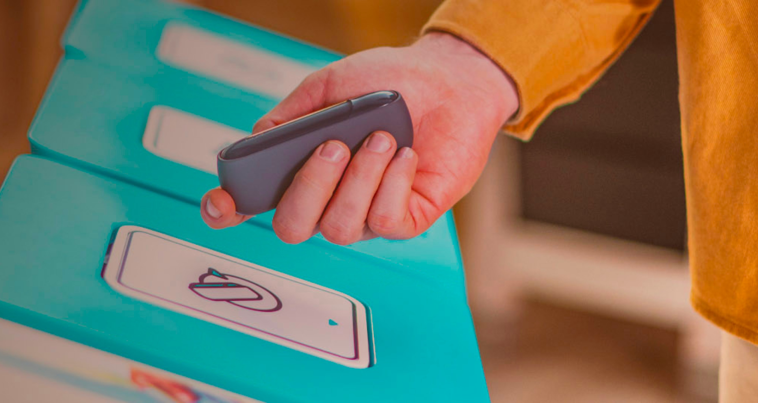 A hand holding IQOS device in front of recycling bin