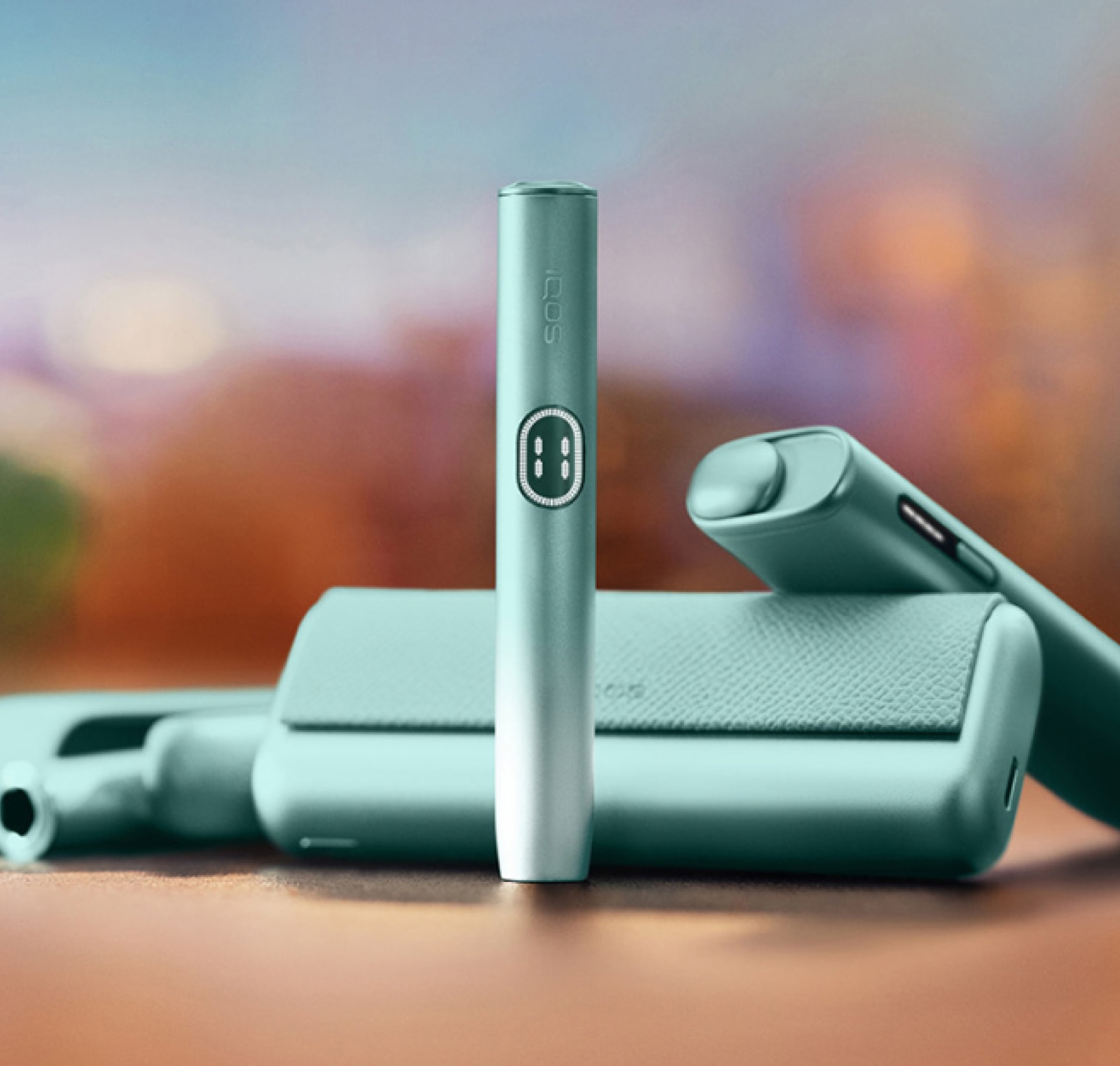 Three IQOS ILUMA i devices next to each other on a blurred orange background.