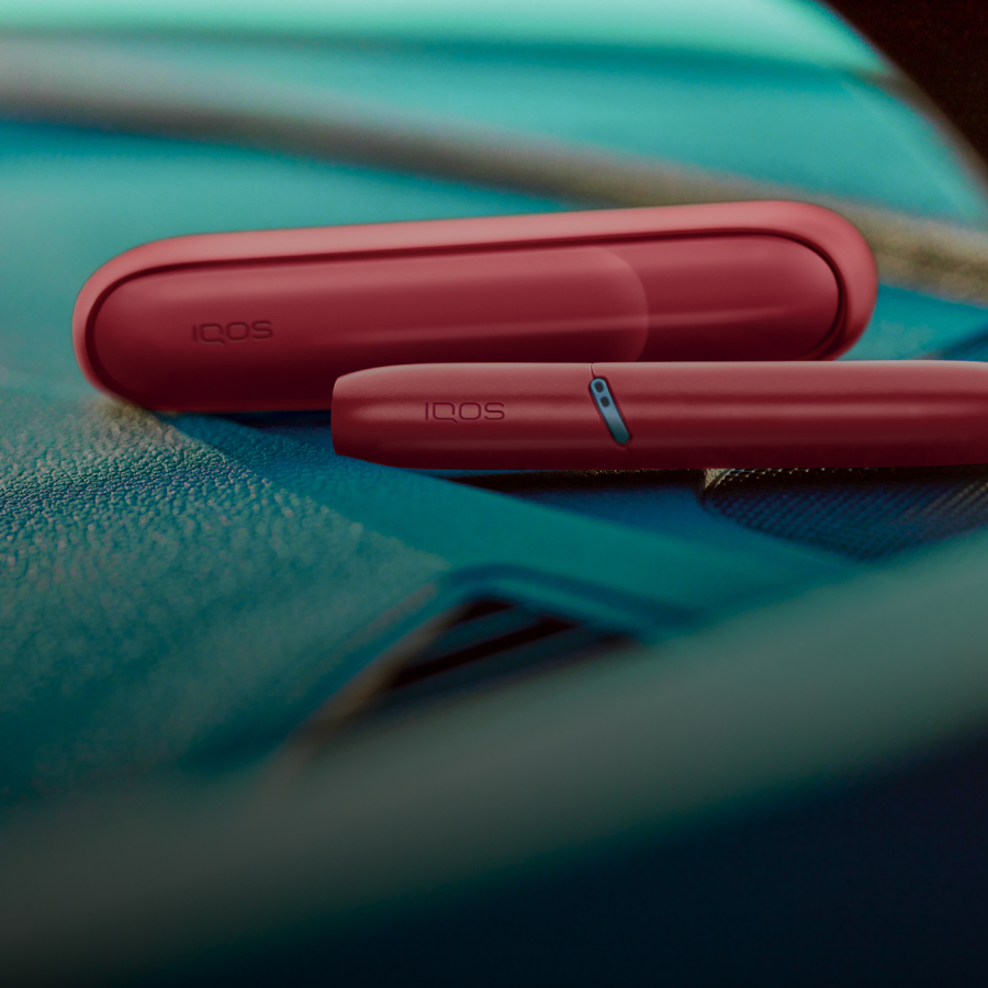 Red IQOS Originals Duo heated tobacco device with case and HEETS stick.