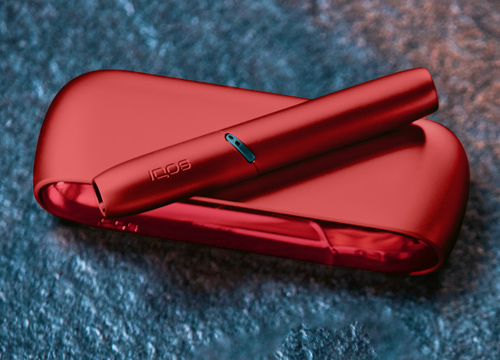 IQOS Originals Duo Holder and Pocket Charger in red color on a coffee table.