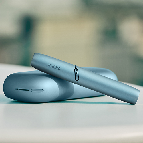 Turquoise IQOS Originals Duo device on a coffee table.