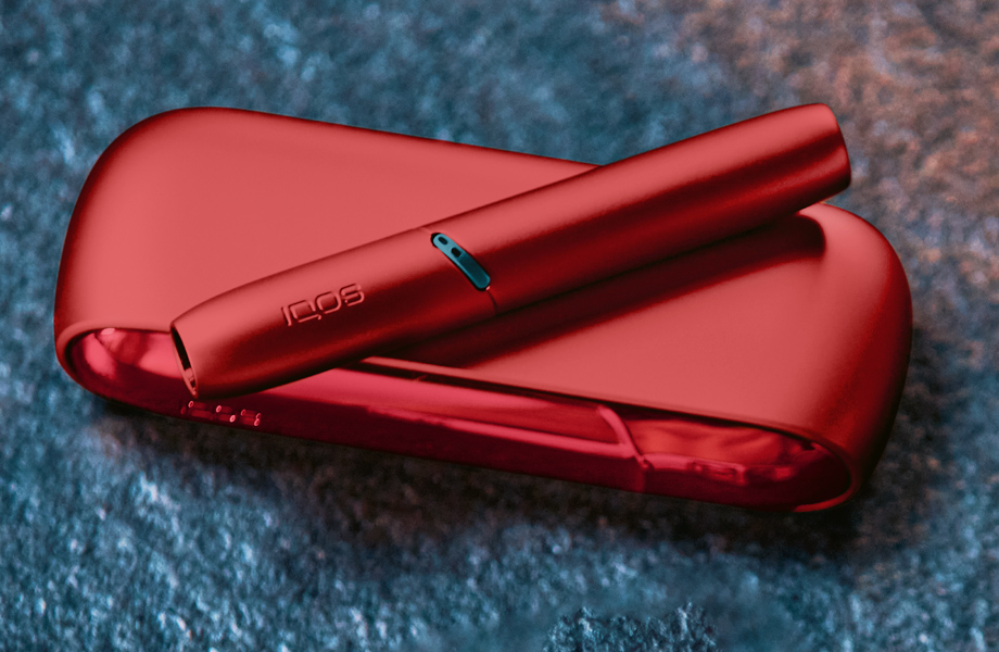 IQOS Originals Duo Holder and Pocket Charger in red color on a coffee table.