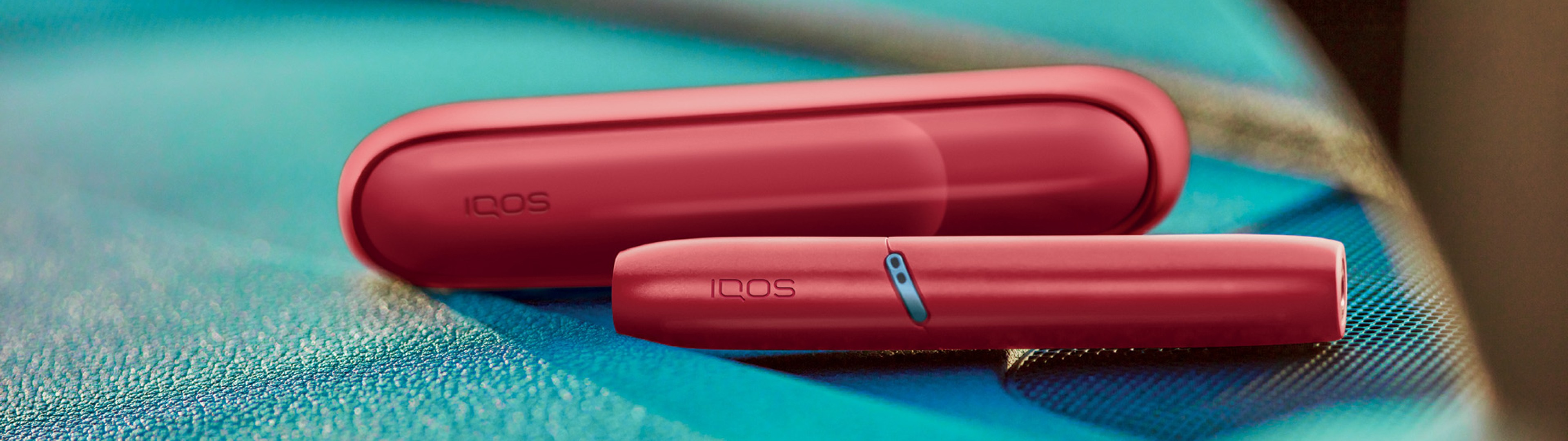 Red IQOS Originals Duo heated tobacco device with case and HEETS stick.